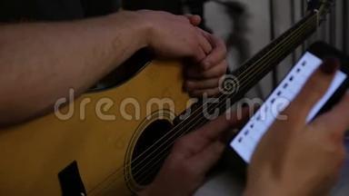 特写双手练习弹吉他，双手拿着手机。 慢动作